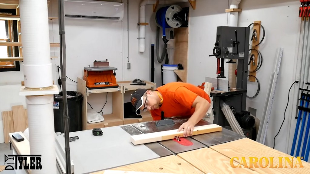 man running wood board through table saw