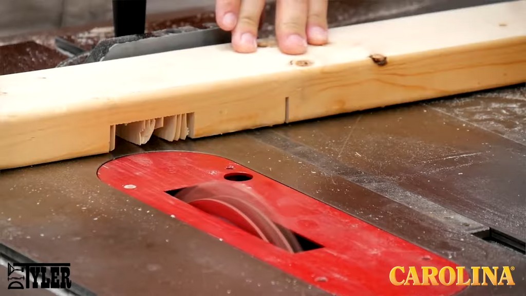 man running wood board through table saw